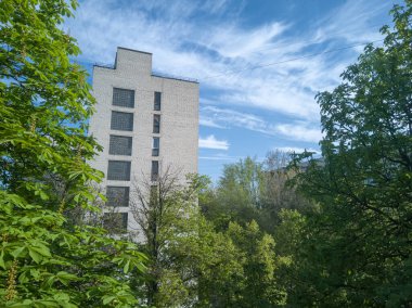 Yeşil ağaçlarda, arkasında güzel mavi gökyüzü olan eski bir Sovyet yerleşim yeri. Yakın plan..