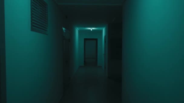 蛍光トルコ色のネオンランプと不気味な暗い廊下で最初の人のビュー 滑らかなぼやけた動きの中で — ストック動画