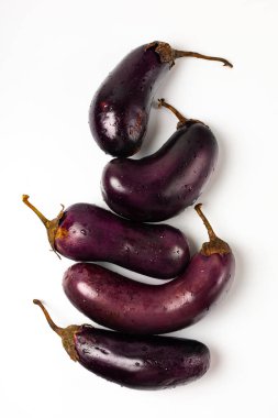 Beyaz zemin üzerinde su damlaları olan taze patlıcan.