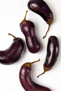 Beyaz zemin üzerinde su damlaları olan taze patlıcan.