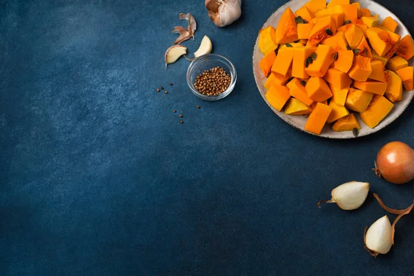 Dilimlenmiş balkabağı ve balkabağı kremalı çorba için diğer malzemeler mavi arka planda.