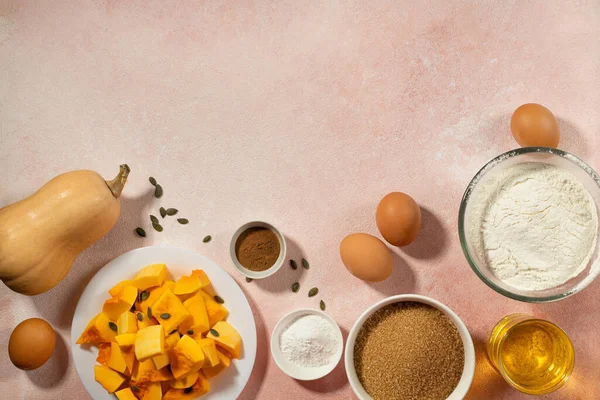 Pumpkin pie ingredients in bowls on pink table