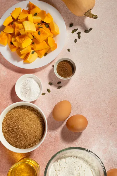 Pumpkin pie ingredients in bowls on pink table