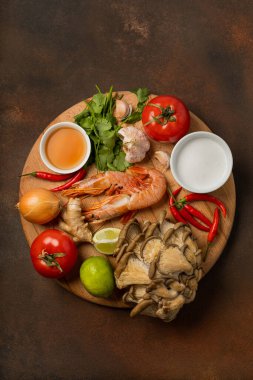 Fresh ingredients of tom yum soup on wooden tray on dark background