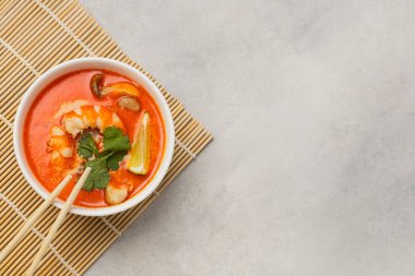 Beyaz kase taze Tom Yum çorbası bambu tezgahında hafif bir arka planda.