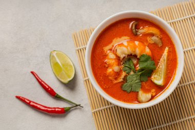 Beyaz kase taze Tom Yum çorbası bambu tezgahında hafif arka planda malzemelerle