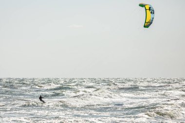 Su sporu. Uçurtma sürmek. Denizde uçurtma. Dalgalarda sörf yapmak. Dalgalarda sörf yap. Dalgıç kıyafetli bir sporcu. Olağanüstü bir hobi. Eğlence olsun diye sörf tahtası. Sudaki adam..