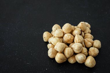 Çikolata için malzemeler. Bir avuç fındık. Hazel meyveleri. İştah açıcı bir resim. Siyah arka planda kavrulmuş fındık. Sağlıklı bir şeyler..