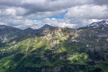 Avusturya Alpleri. Grossglockner Dağı. Yazın İskoçya. Bulutların gölgesindeki yüksek dağlar ve güneş ışınları. Dağ manzarası. Sulu sebzeler. Bulutlu gökyüzü.