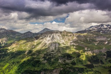 Avusturya Alpleri. Grossglockner Dağı. Yazın İskoçya. Bulutların gölgesindeki yüksek dağlar ve güneş ışınları. Dağ manzarası. Sulu sebzeler. Bulutlu gökyüzü.