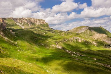 Avusturya Alpleri. Grossglockner Dağı. Yazın İskoçya. Bulutların gölgesindeki yüksek dağlar ve güneş ışınları. Dağ manzarası. Sulu sebzeler. Bulutlu gökyüzü.