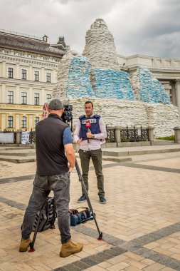 Askeri muhabir. Televizyon gazetecisi. Kamera ekibi. Savaş sırasında Ukrayna 'dan rapor geldi. Kum torbalı barikatların arka planında gazeteci.