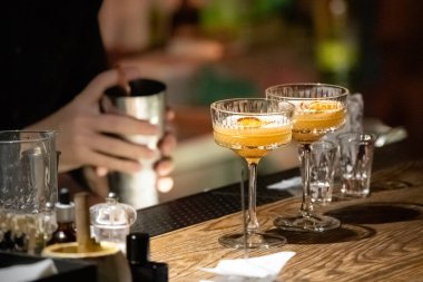 İki kokteyl. Parlak içkili bardaklar. Barmenlik işi. Turuncu alkollü içecekler. Soğutucu içecek. Gece hayatı.