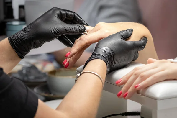 Beauty industry. Manicure salon. Female hands. Self care. Cosmetological gloves. Red nail polish.