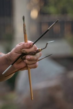 Artist's hand with brushes, spatula and other tools. Artist's tools. Hand with brushes and spatulas. Creative personality. Creative profession. Work with paints. Paint with oil and paint.