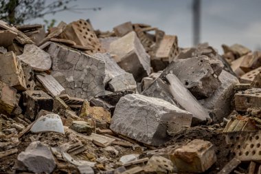 Stone dump on the ruins of a private house. A pile of construction debris and stones. Remains of bricks in a bucket.