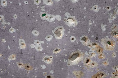 Bullet marks. A fence cut by shrapnel. Iron, pierced by shells. War in Ukraine. Russian aggression. Shooting civilians. Mutilated housing.