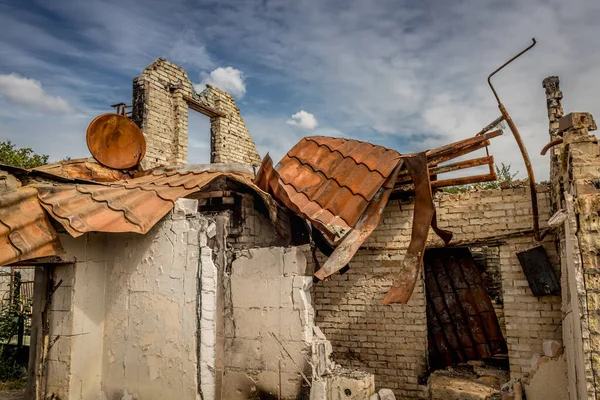 Ruins of a private house. Burnt house. A rusty satellite dish. Ruined life. Remains of the building. War in Ukraine. Burnt house. Missile hit.