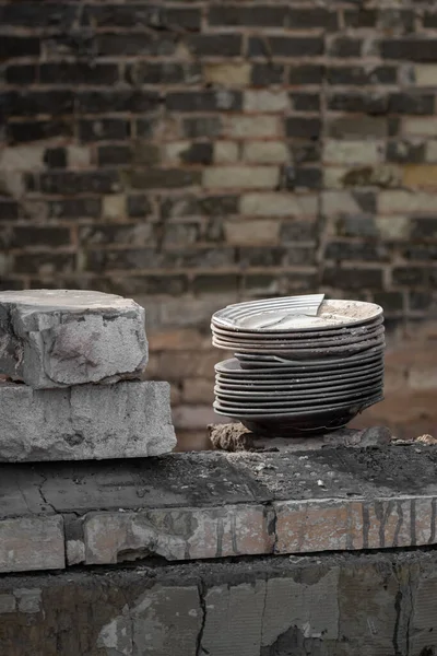 A stack of plates in the middle of a war-torn house. Findings of things in the ruins of the house. Plates on the windowsill. The rest of things. Ruined life. War in Ukraine.