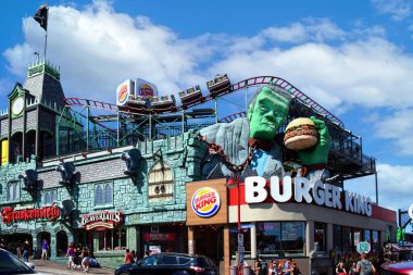 Niagara Falls, Canada - August 13, 2022: The House of Frankenstein with rollercoaster ride, Beaver Tails and Burger King on Clifton Hill, an area with many tourist attractions.
