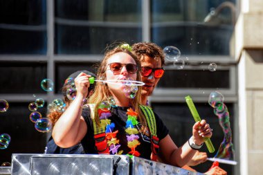 Ottawa, Canada - August 28, 2022: A woman firefighter playfully blows bubbles from fire truck at the Gay Pride Parade in Ottawa.