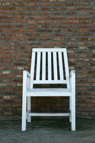 Wooden chair against brick wall — Stock Photo, Image