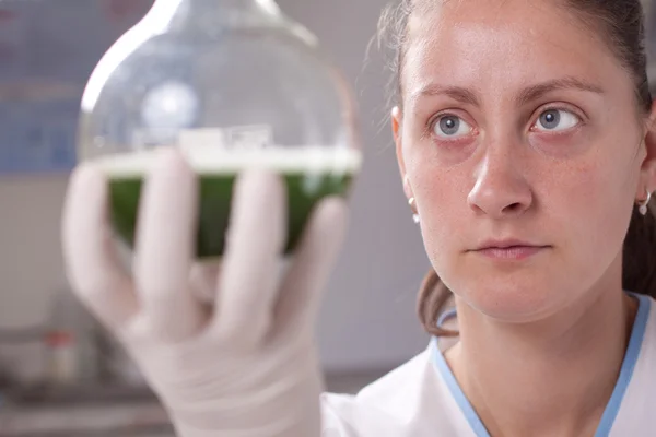 Femme examiner les bouteilles colorées remplir de produits chimiques — Photo