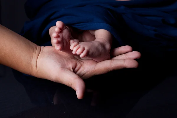 Mãe mão segurando bebê pés — Fotografia de Stock