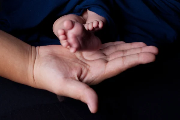 Mãe mão segurando bebê pés — Fotografia de Stock