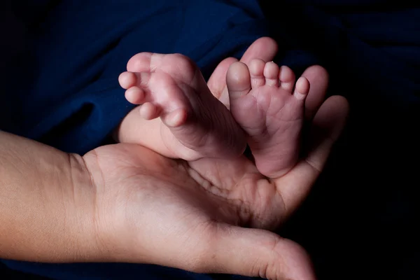 Madre mano sosteniendo pies de bebé — Foto de Stock