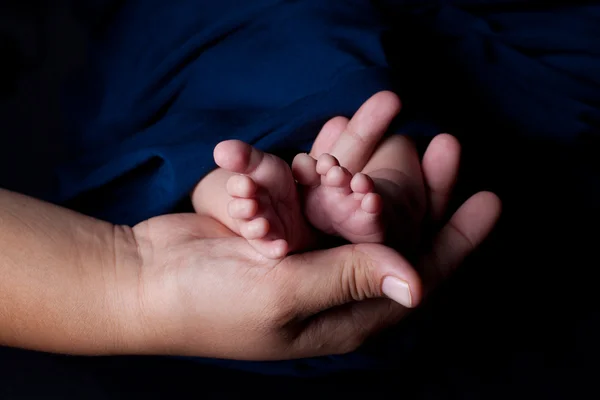 Madre mano sosteniendo pies de bebé — Foto de Stock