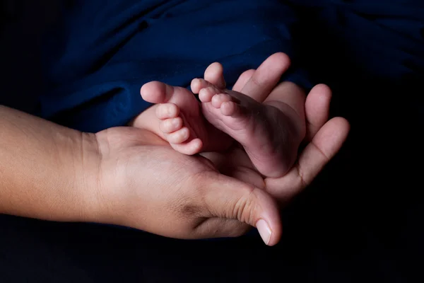 Matka ręka trzyma stopy dziecka — Zdjęcie stockowe