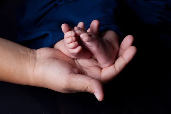 Mors hånd som holder babyføtter – stockfoto