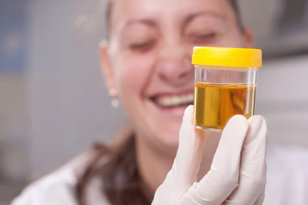 Woman examine urine container — Stock Photo, Image