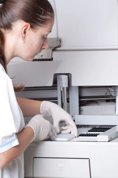 Mujer cargando muestras en analizador bioquímico —  Fotos de Stock