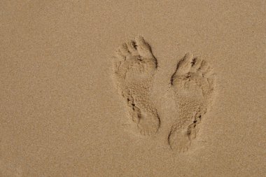 Kumsaldaki ıslak kumda ayak izlerinin manzarası.