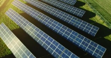 Güneş panellerinin inanılmaz günbatımı görüntüsü yeşil alanlarda bir sırada duruyor. Güneşten yenilenebilir ekolojik enerji kaynağı. Mavi güneş panelinde muhteşem bir güneş parlıyor..