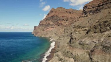 Gran Kanarya adasının batısındaki Playa de Guigui kumsalı. Plaja sadece yürüyerek ya da tekneyle ulaşılabilir. Büyük kayalıkların ve kayalıkların yukarıdan görünüşü.