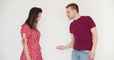 Beyaz arka planda dikildiğini iddia eden genç beyaz bir adam ve sinirli esmer kadın. Kırmızı elbiseli zarif bir kız ve günlük giysili bir adam. Ayrılma, aldatma, boşanma, konsept.