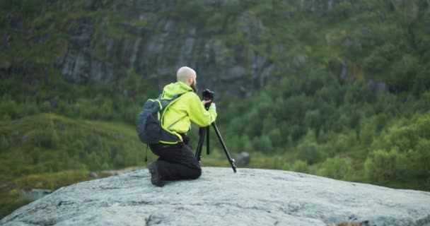 身穿绿色夹克的景观摄影师拍了一张绿色森林的照片 徒步旅行者把相机放在三脚架上拍照 — 图库视频影像