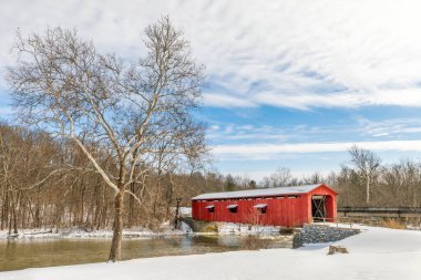 Tarihsel kırmızı Katarakt Köprüsü, kırsal Owen County, Indiana 'da Mill Creek' i geçiyor güneşli bir kış günü kar manzarayı kaplıyor..