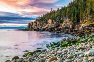 Gün doğumu, Acadia Ulusal Parkı 'ndaki Boulder Sahili' ndeki Otter Kayalıkları 'nda gökyüzünü renklerle boyar ve sıcacık bir şekilde parlar. Issız Ada, Maine.