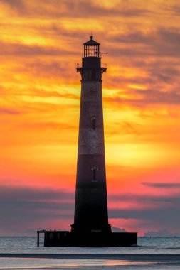 Folly Sahili 'nden çekilen, renkli bir gündoğumu gökyüzü silueti Atlantik kıyısındaki tarihi Morris Adası Deniz Feneri Charleston, Güney Carolina yakınlarındaki.