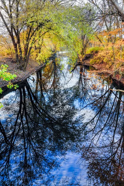 Podzimním Dni Zamračenou Modrou Oblohou Stromy Podzimními Barvami Listí Odrážejí — Stock fotografie