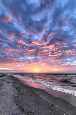 Hafif dalgalar şafakta kopar dramatik ve renkli bir gündoğumu gökyüzü Meksika Körfezi 'ndeki Sanibel Adası, Florida' daki ıslak kumlu plajı yansıtır..