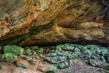 Colorful rock boulders litter the floor beneath the ceiling of one of the secluded Saltpetre Caves, a series of sandstone recess caverns in Hocking Hills region of southeast Ohio.