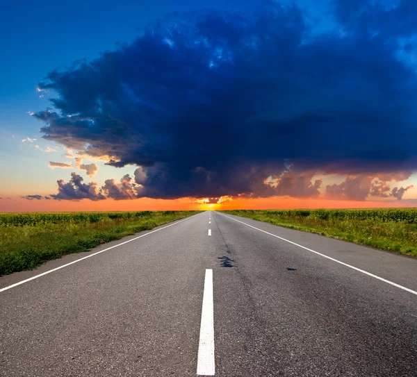 Route asphaltée vers un coucher de soleil — Photo