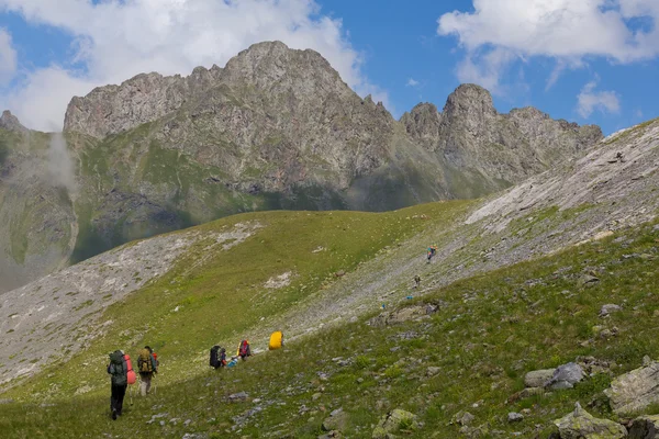 Turistas caminando por una ladera montañosa — Foto de Stock