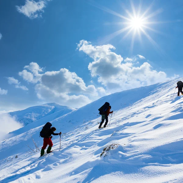 Hiker upwards a snow slope — Stock Photo, Image