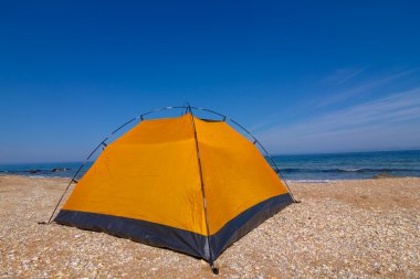 kumlu bir plaj üzerinde sarı turistik çadır